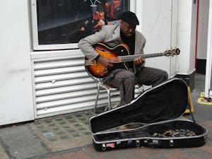 Man in a Black Hat Playing Guitar on a Pavement