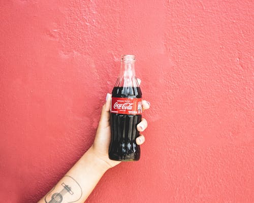 Free A Person Holding a Bottle of Coca Cola Stock Photo