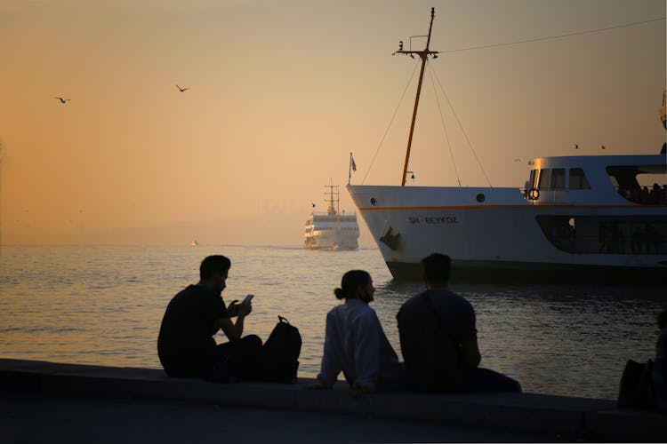 Silhouette Of People At Sunrise And Ships On Sea