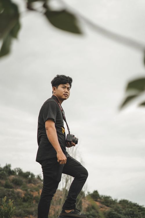 Free Asian man holding a camera outdoors in Kepulauan Riau, Indonesia. Stock Photo