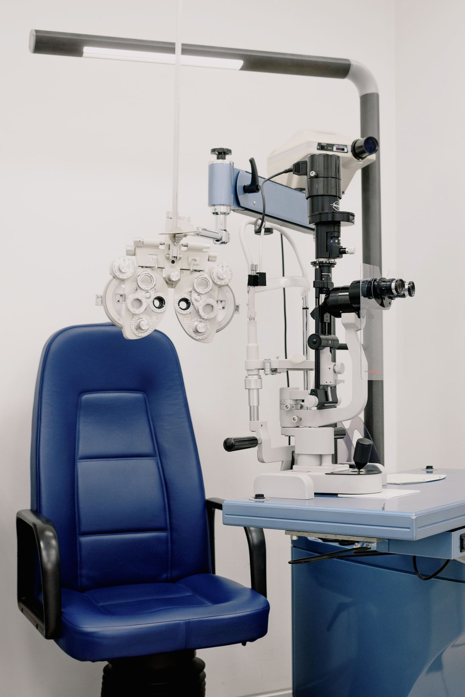 A blue examination chair and optical equipment in a light-filled room