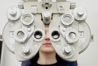 Woman diagnosing vision on refractor testing device during eye examination in modern ophthalmology clinic