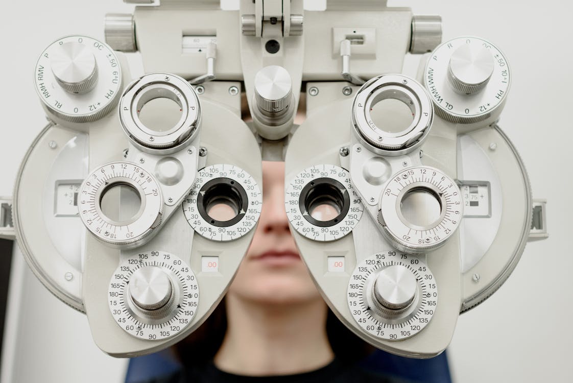 Free Woman diagnosing vision on refractor testing device during eye examination in modern ophthalmology clinic Stock Photo