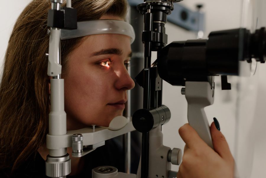 An eye doctor performing a slit-lamp examination — the exam used to distinguish normal age-related floaters from a retinal tear