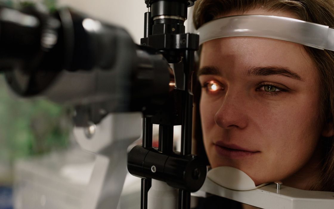 Patient looking into a slit-lamp microscope while the front of her eye is examined