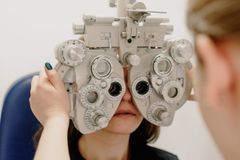 Unrecognizable female ophthalmologist adjusting medical equipment while doing vision check up of patient in contemporary clinic during work