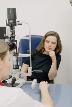A woman sits across an ophthalmologist during an eye examination in a clinic.