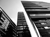 这张黑白照片从低角度拍摄，突显了现代城市摩天大楼的引人注目之处