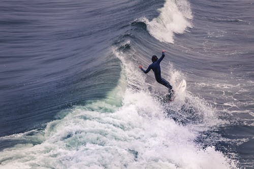 Person in a Wetsuit Surfing at the Sea