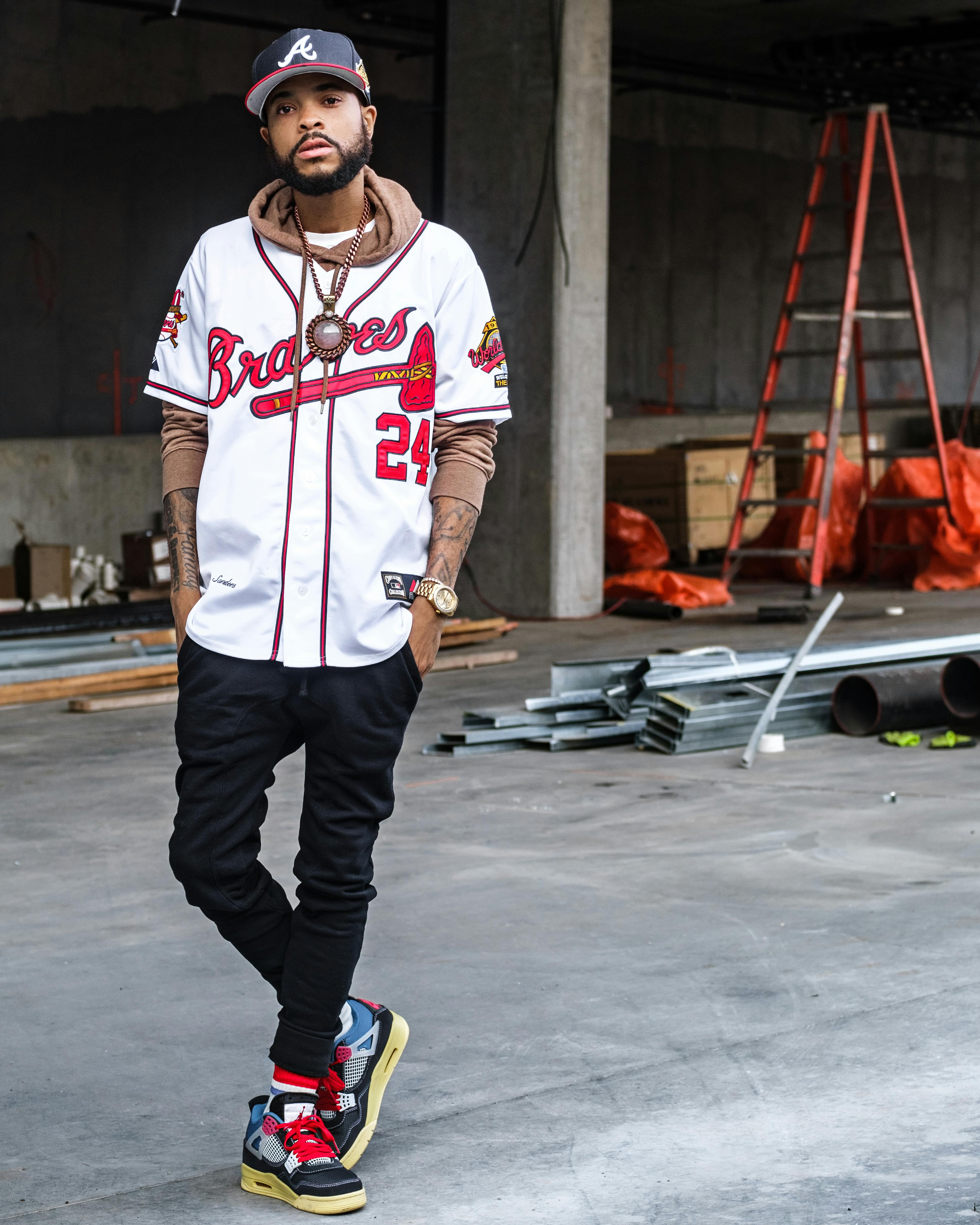 photograph of a man with a cap posing with his hands in his pockets