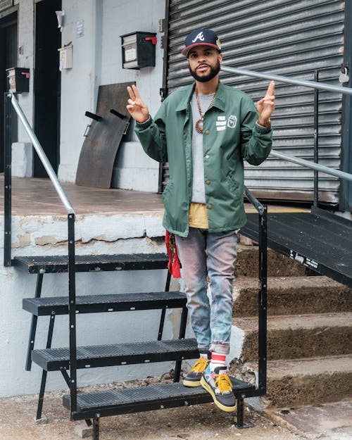 Photo of a Man in a Green Jacket Doing the Peace Sign