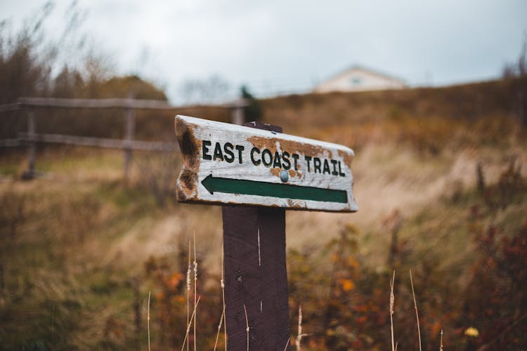 Guide Post With Inscription And Arrow In Countryside