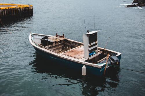 Free From above of old wooden traditional fishing boat moored on rippling sea water on cloudy day Stock Photo