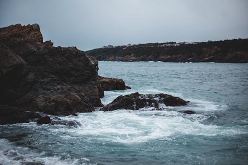 Free Rocky formations in stormy ocean under overcast sky Stock Photo