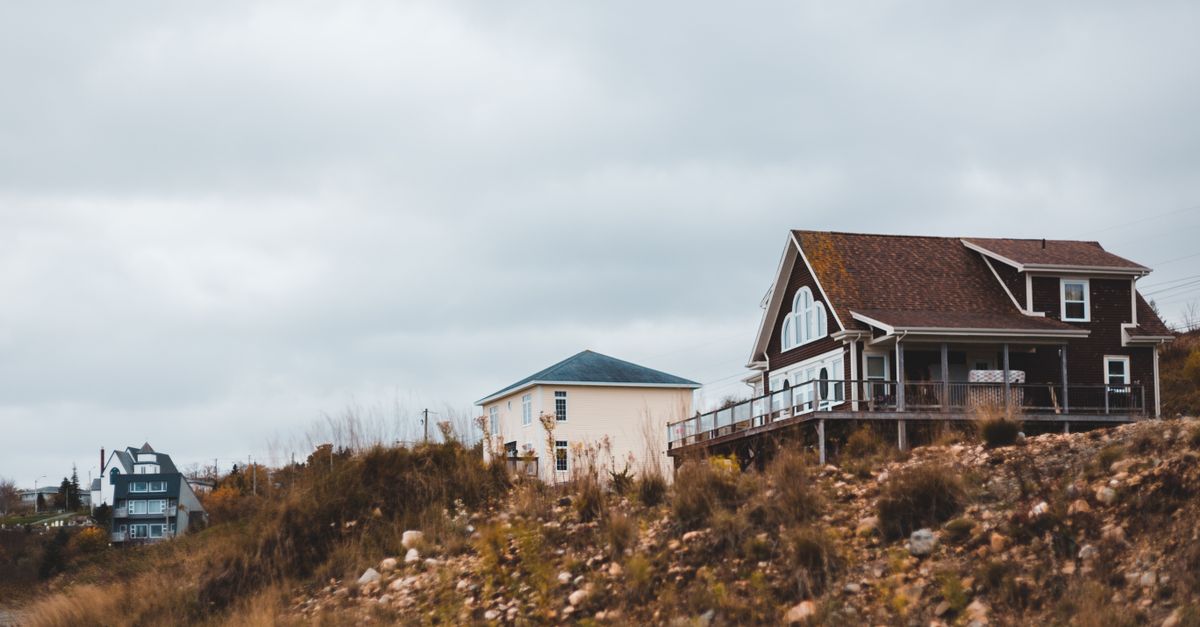From below of typical residential houses located on grassy hill against overcast sky in countryside