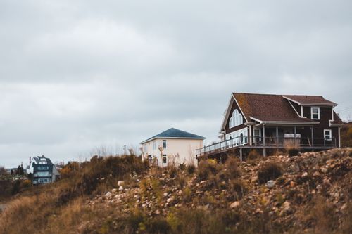 Free From below of typical residential houses located on grassy hill against overcast sky in countryside Stock Photo