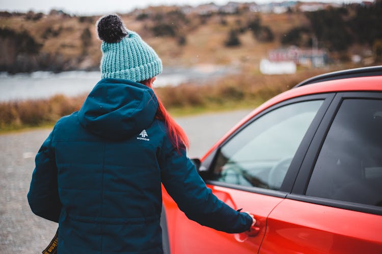 Young Woman Opening Door Of Red Car