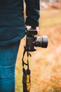 Crop anonymous person standing with photo camera in hand in path with yellow grass