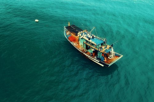 Free Drone view of traditional ship sailing on rippling turquoise sea on sunny day Stock Photo