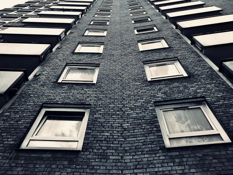A monochrome view of a brick high-rise building from a low angle, emphasizing architecture and symmetry.