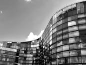 现代黑白照片中，一座带有反光玻璃窗的弧形摩天大楼矗立着