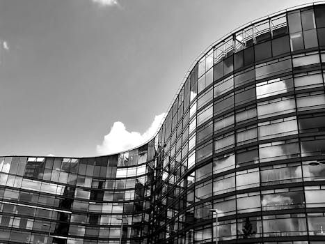 现代黑白照片中，一座带有反光玻璃窗的弧形摩天大楼矗立着