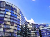 弧形建筑以玻璃板映照天空和云层，展现出其现代设计