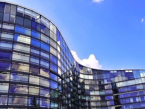 弧形建筑以玻璃板映照天空和云层，展现出其现代设计