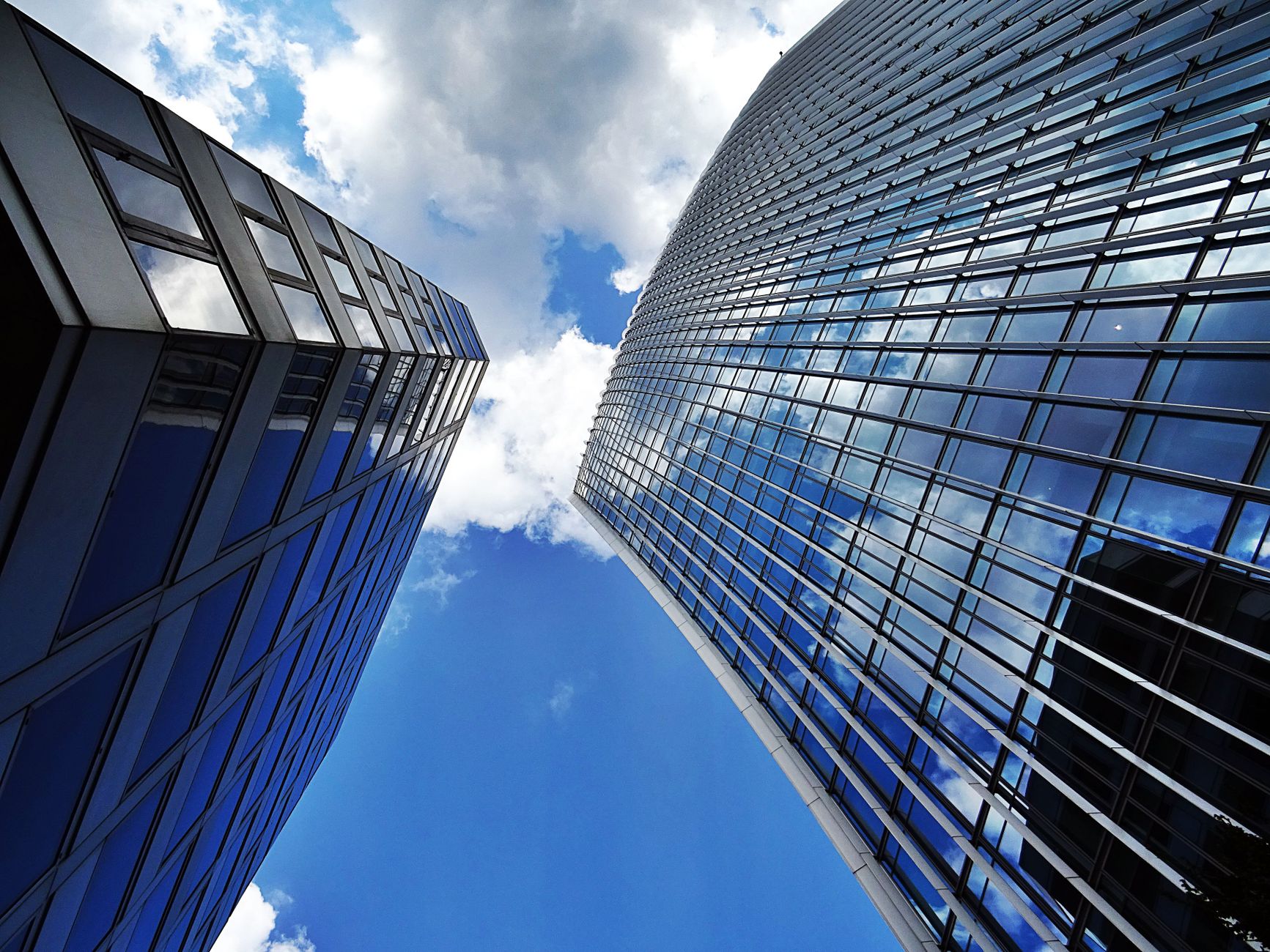 Stunning low angle shot of modern skyscrapers with glass facades and reflections against a blue sky.