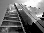 从低角度拍摄一座现代玻璃建筑，倒映着天空，展现了建筑设计之美