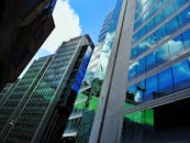 现代摩天大楼的玻璃外墙反射着蓝天和云彩，从低角度看去