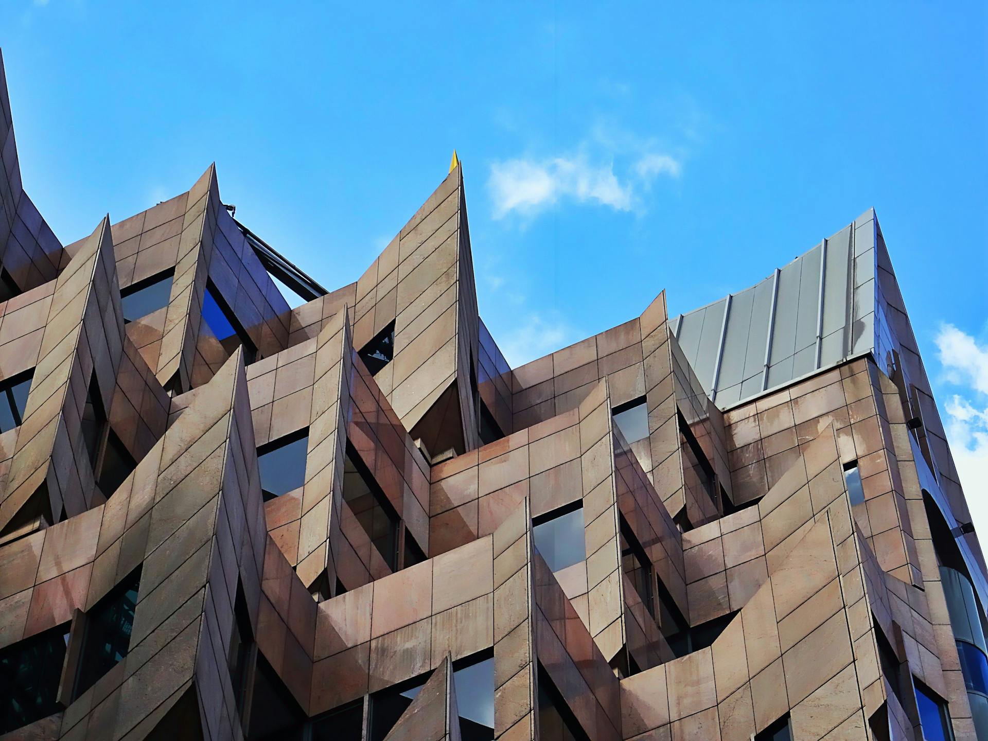 Futuristic architectural design with sharp angles and a striking facade under a clear blue sky.