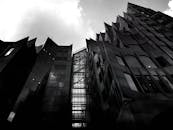 一张黑白照片，以低角度拍摄现代摩天大楼的戏剧性立面