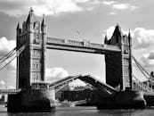 这张令人惊叹的黑白照片中，伦敦塔桥高耸入云，天空多云