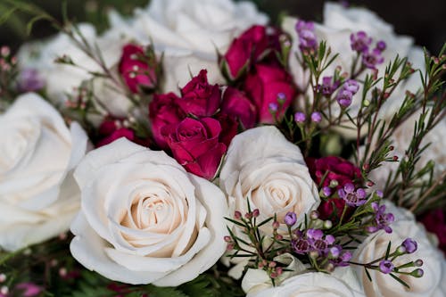 From above elegant bouquet of white and red roses composed with tiny gentle wildflowers