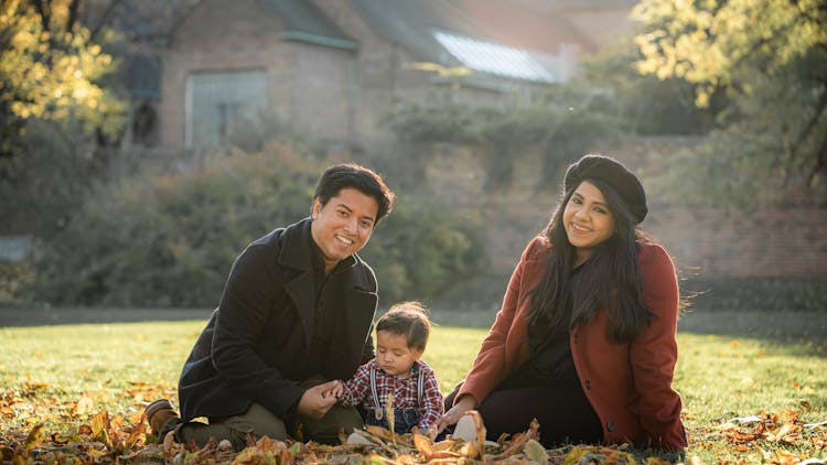 Loving Ethnic Family With Small Cute Son On Autumn Lawn