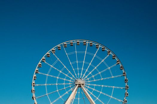 Iconic Ferris wheel in Montréal against a vibrant blue sky, showcasing urban leisure.