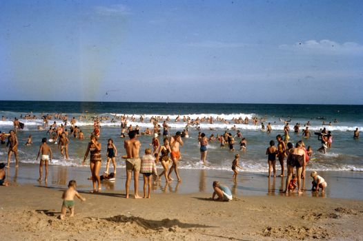 Vibrant scene of people enjoying leisure time on a busy beach in summer.