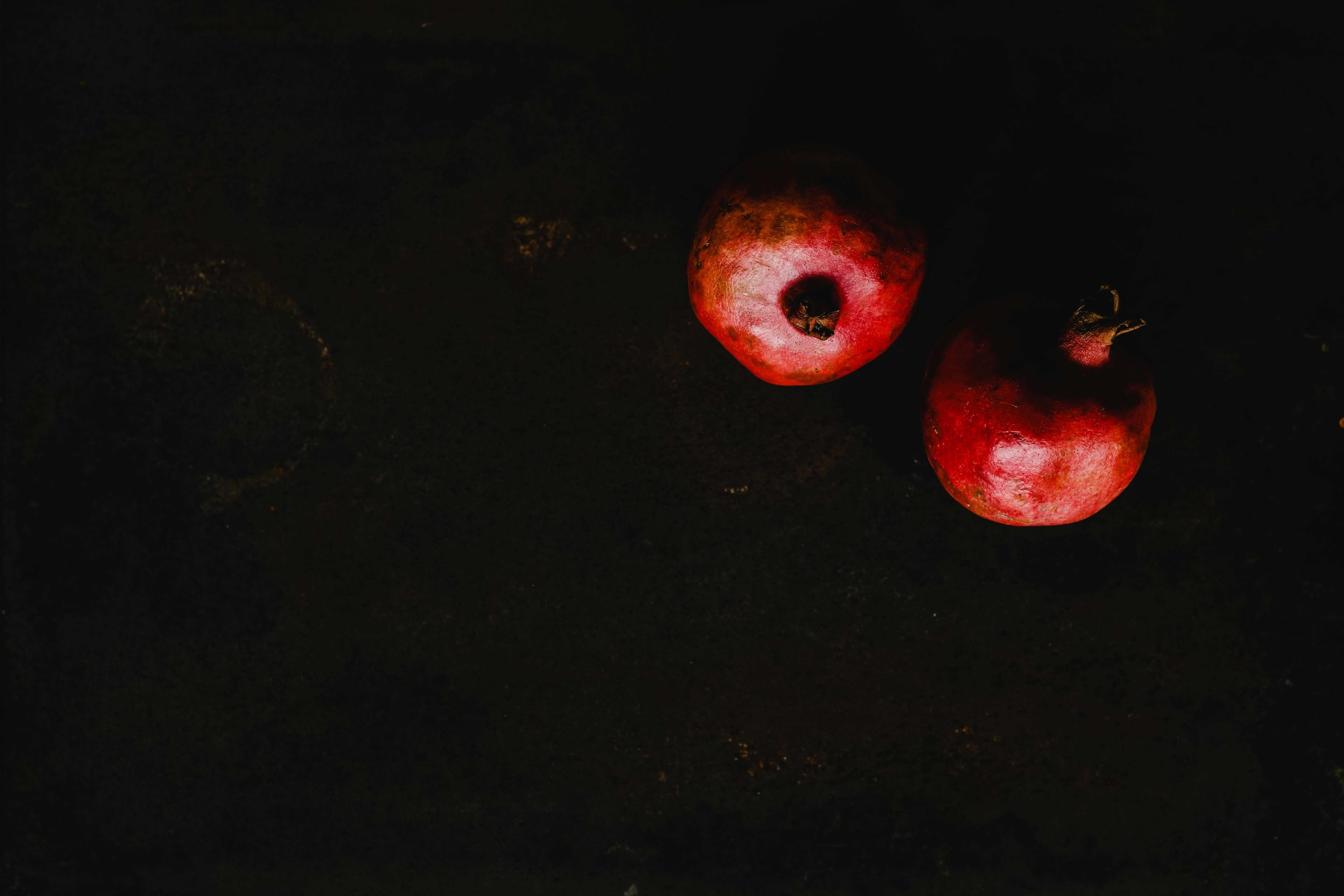 Two ripe pomegranates on a dark background create a striking and artistic composition.