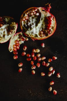 Artistic shot of pomegranate seeds cascading on a dark surface, emphasizing texture and color contrast.