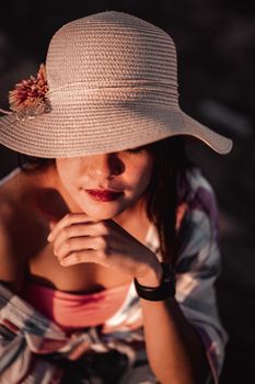 一位衣着时尚、戴着帽子的匿名女性，在阳光明媚的日子里平静地托着下巴