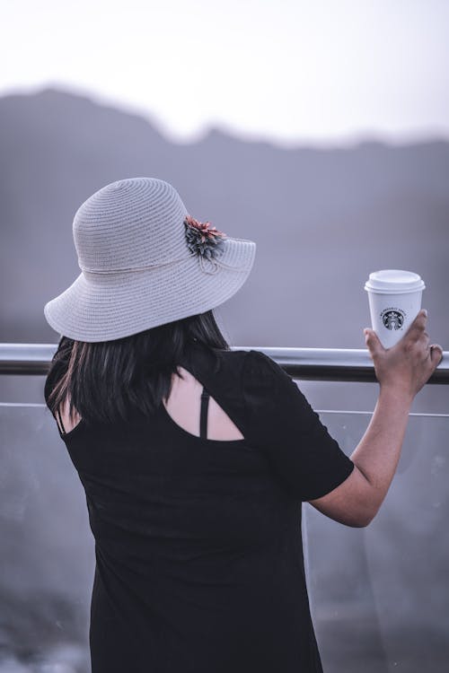 Woman standing with cup of coffee on glass balcony