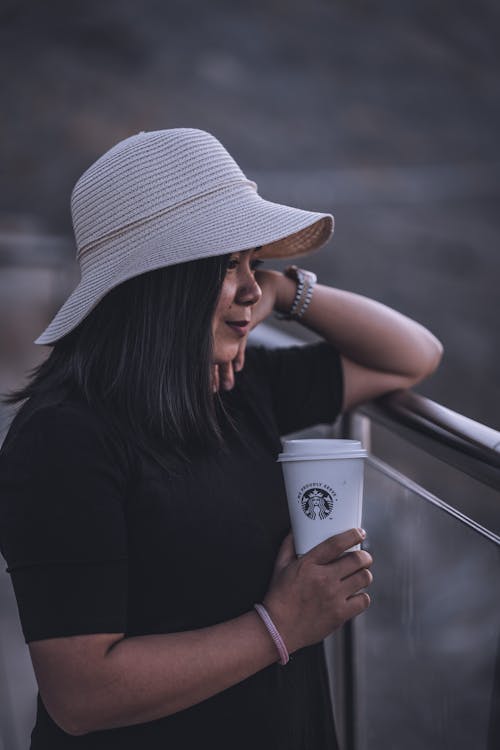 Pensive woman with cup coffee standing on balcony