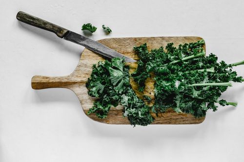 Free Fresh organic kale on a wooden chopping board with a knife, ready for preparation. Stock Photo
