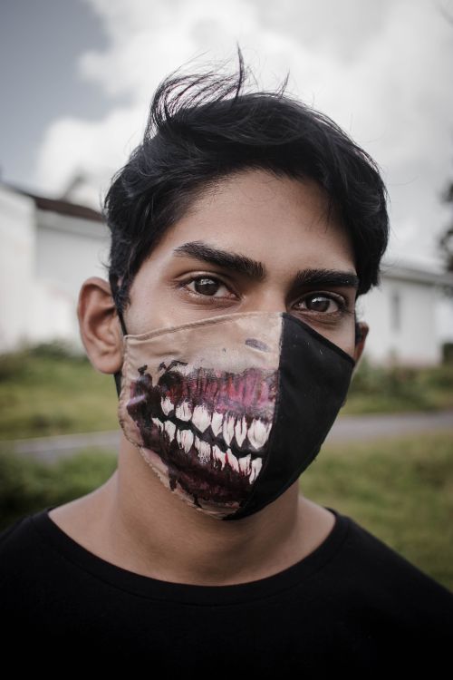 Free Portrait of a man wearing a unique artistic face mask outdoors with blurred background. Stock Photo