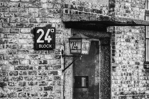 Black and white photo of Block 24 entrance in Auschwitz, Oświęcim. Grayscale architecture.