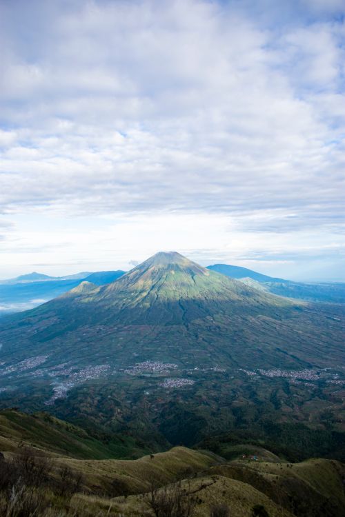 Free Breathtaking view of volcanic mountain range against grassy hills under sky with clouds Stock Photo