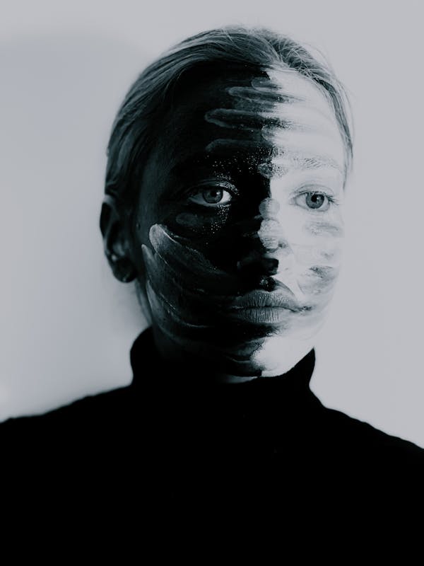 Emotionless young lady with smears on painted face looking away in studio