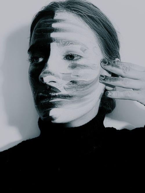 Free Black and white of young tranquil female model smearing artistic makeup with hand after photo shoot Stock Photo
