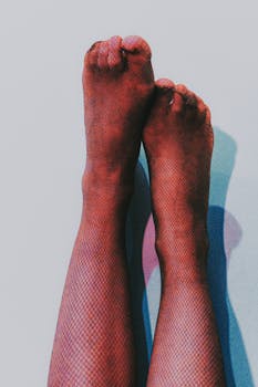Close-up shot of feet in fishnet stockings against a light background, with artistic shadow play.